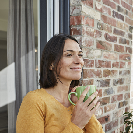 Young Professionals Jumbo Loan Program woman standing outside drinking coffee