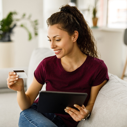 Woman with tablet and debit card looking at debit card