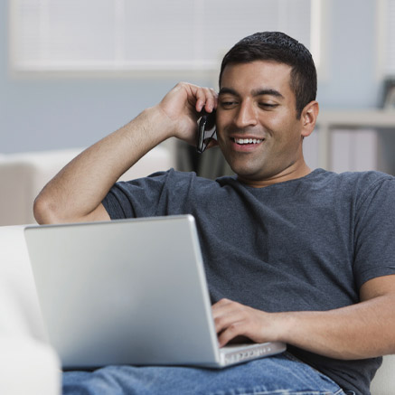 man talking on the phone and looking at laptop