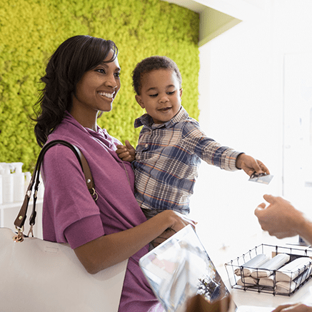 Make it Easier for Customers to Pay mother holding child who is handing clerk credit card